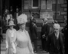 Queen Mary and King George V Accompanied by a Group of Officials Emerging from a Building , 1924. Creator: British Pathe Ltd
