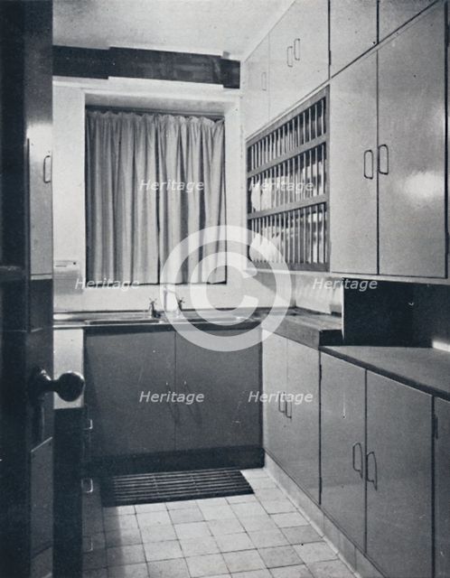 'R. W. Symonds and Partner, L. & A.R.I.B.A. - Kitchen: Putty-coloured cellulosed fiitments, stainles Artist: Unknown.