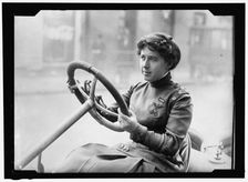 Race car driver Joan Newton Cuneo, seated in racing car, facing left, between 1910 and 1917. Creator: Harris & Ewing