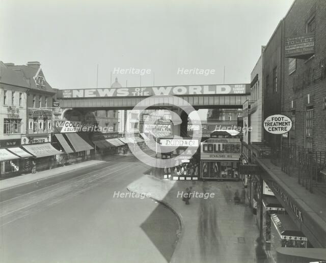 Railway bridge and advertising over the Brixton Road, Lambeth, London, 1938. Artist: Unknown.