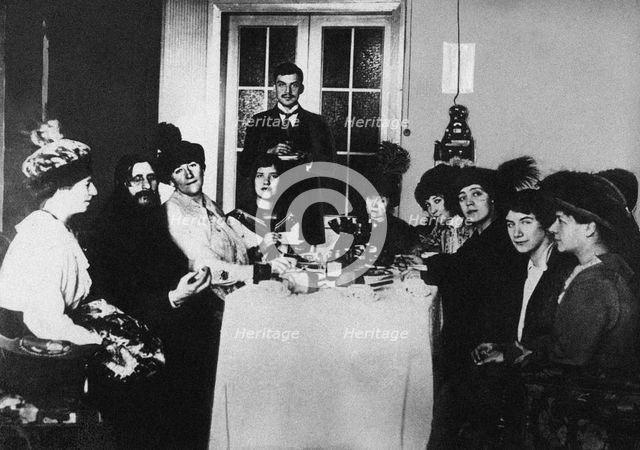Rasputin (second from left) at the meal among His Admirers, c. 1910.