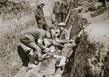 Red Cross men in the trenches tend a wounded man, Somme campaign, France, World War I, 1916