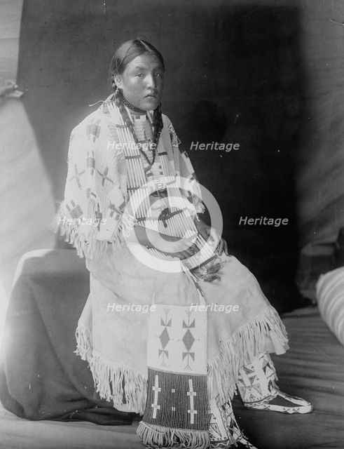 Red Elk Woman, a Sioux girl, full-length portrait, seated, facing right, c1907. Creator: Edward Sheriff Curtis.