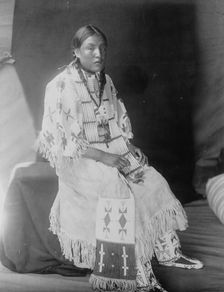 Red Elk Woman, a Sioux girl, full-length portrait, seated, facing right, c1907. Creator: Edward Sheriff Curtis