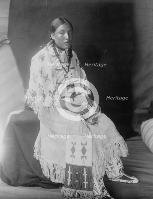 Red Elk Woman, a Sioux girl, full-length portrait, seated, facing right, c1907. Creator: Edward Sheriff Curtis.