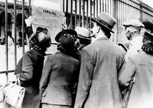 Refugees studying a train timetable, Gare de l'Est, Paris, July 1940