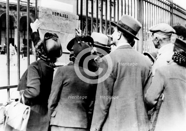 Refugees studying a train timetable, Gare de l'Est, Paris, July 1940. Artist: Unknown