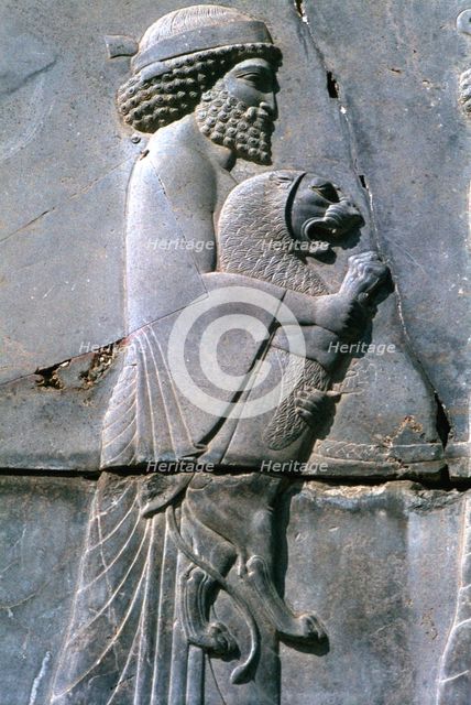 Relief of a man holding a lion cub, Persepolis, Iran. Creator: Vivienne Sharp.