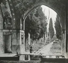 Reproduction of print showing Garden at Fin-Nahe¯, Kashan, Iran. Man seated under arch , c1920. Creator: Frances Benjamin Johnston
