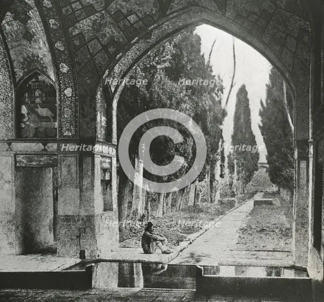 Reproduction of print showing Garden at Fin-Nahe¯, Kashan, Iran. Man seated under arch , c1920. Creator: Frances Benjamin Johnston.