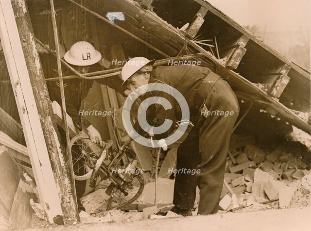 Rescue workers reteieving a bicycle from a wrecked Warden's Post, London. Creator: Unknown.
