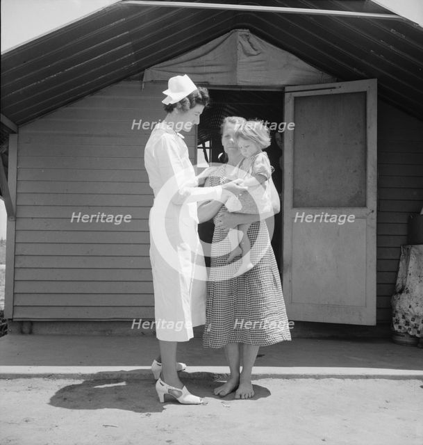 Resident nurse come to visit family, FSA camp, Farmersville, Tulare County, 1939. Creator: Dorothea Lange.