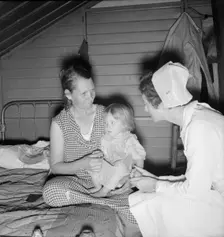 Resident nurse interviews mother and examines sick baby, FSA camp, Farmersville, CA, 1939. Creator: Dorothea Lange