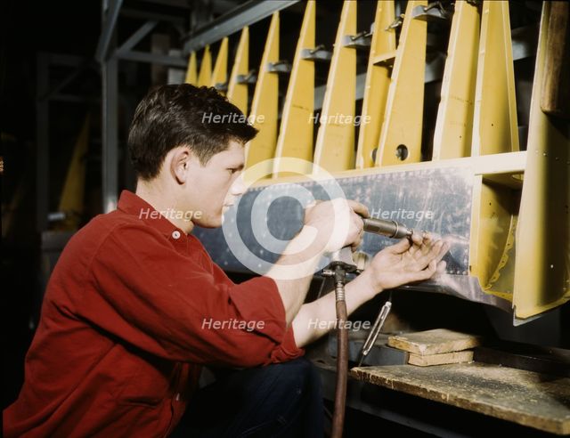 Riveter at work at the Douglas Aircraft Corporation plant in Long Beach, Calif., 1942. Creator: Alfred T Palmer.
