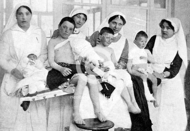 Wounded children from Ypres with nurses at La Panne, Belgium, First World War, 1914-1918, (c1920). Artist: Unknown