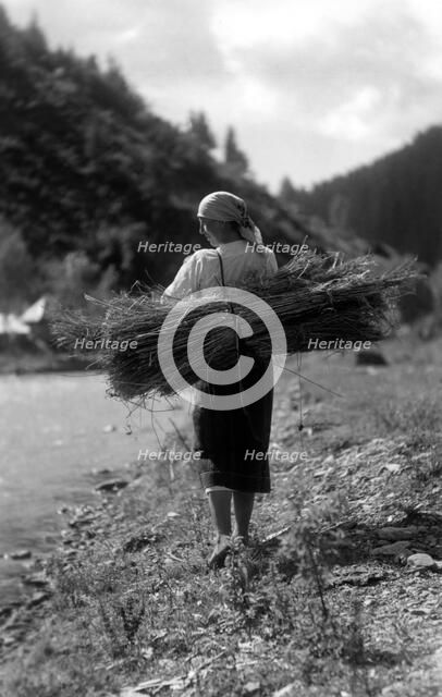 Woman carrying a bundle of sticks, Bistrita Valley, Moldavia, north-east Romania, c1920-c1945. Artist: Adolph Chevalier