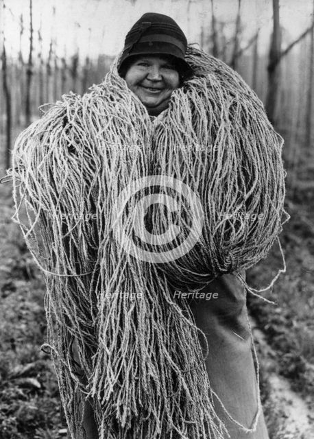 Woman carrying a large bundle of string or fibre, c1937. Creator: Unknown.