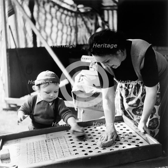 Woman and child at Hampstead fun fair, London, (early 1950s?). Creator: Henry Grant.