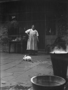 Woman and rabbit in a courtyard, New Orleans, between 1920 and 1926. Creator: Arnold Genthe