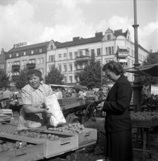 Woman buying potatoes from a fruit and vegetable stall in the market, Malmö, Sweden, 1947. Creator: Otto Ohm