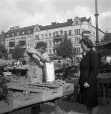 Woman buying potatoes from a fruit and vegetable stall in the market, Malmö, Sweden, 1947. Creator: Otto Ohm