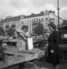 Woman buying potatoes from a fruit and vegetable stall in the market, Malmö, Sweden, 1947. Creator: Otto Ohm