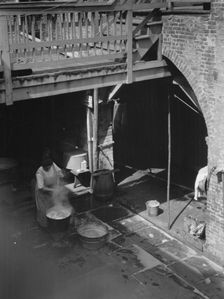 Woman doing laundry in a courtyard, New Orleans, between 1920 and 1926. Creator: Arnold Genthe