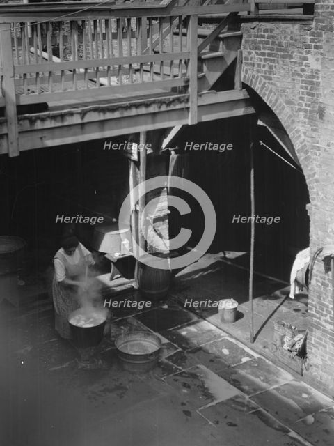 Woman doing laundry in a courtyard, New Orleans, between 1920 and 1926. Creator: Arnold Genthe.