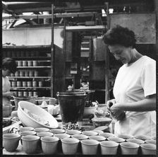 Woman fixing handles to mugs prior to firing in a pottery works, Stoke-on-Trent, 1965-1968. Creator: Eileen Deste