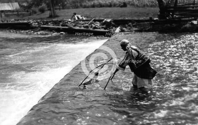 Woman fishing above a weir, Bistrita Valley, Moldavia, north-east Romania, c1920-c1945. Artist: Adolph Chevalier
