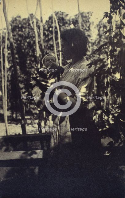 Woman holding an infant outdoors, between 1920 and 1940. Creator: Unknown.