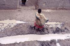 Woman in muddy street, Mopti, Mali, 1990. Creator: Amanda Waite