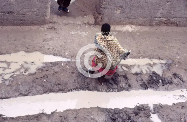 Woman in muddy street, Mopti, Mali, 1990. Creator: Amanda Waite.