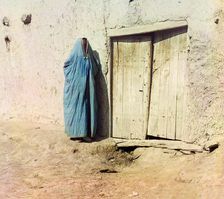 Woman in purdah, standing near wooden door, between 1905 and 1915. Creator: Sergey Mikhaylovich Prokudin-Gorsky