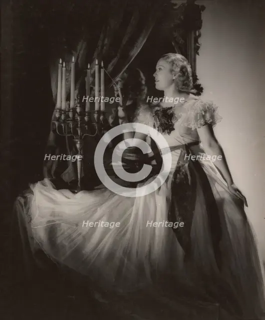 Woman lighting candelabra, 1930s. Creator: Gunther Krampf.