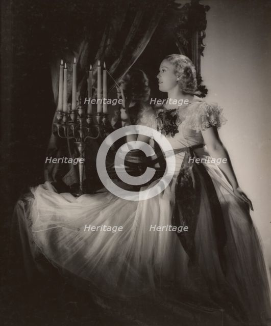 Woman lighting candelabra, 1930s. Creator: Gunther Krampf.
