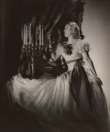 Woman lighting candelabra, 1930s. Creator: Gunther Krampf