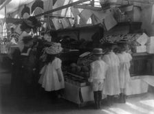 Woman schoolteacher and group of young pupils examining fruits and vegetab...Washington DC. (1899?). Creator: Frances Benjamin Johnston
