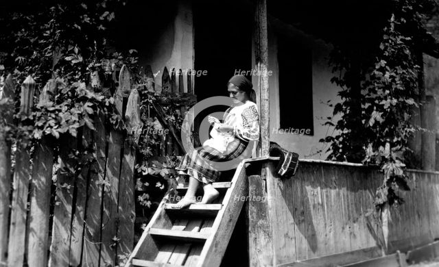 Woman sewing on her porch steps, Bistrita Valley, Moldavia, north-east Romania, c1920-c1945. Artist: Adolph Chevalier