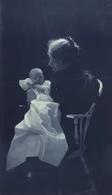 Woman, sitting in chair, holding an infant, full-length portrait, c1900. Creator: Sarah J. Eddy