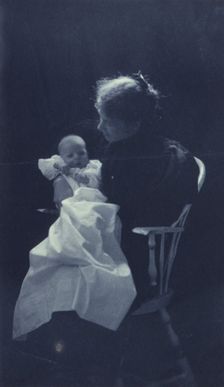 Woman, sitting in chair, holding an infant, full-length portrait, c1900. Creator: Sarah J. Eddy