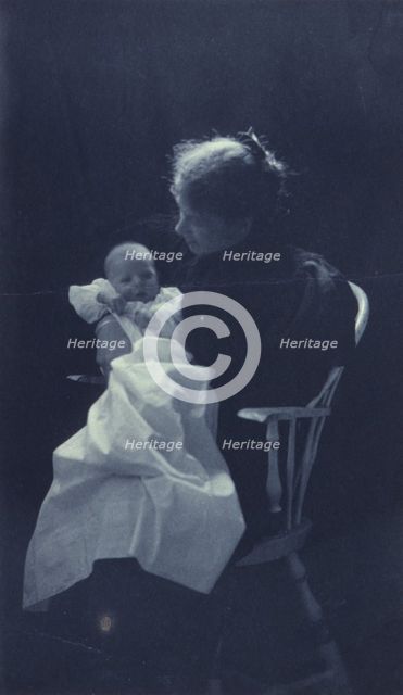 Woman, sitting in chair, holding an infant, full-length portrait, c1900. Creator: Sarah J. Eddy.
