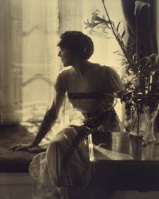 Woman sitting on window seat, looking left, full-length portrait, between 1900 and 1920. Creator: Unknown