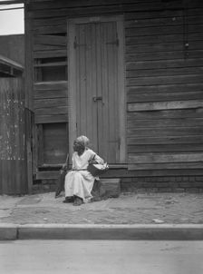 Woman sitting on steps holding a basket, New Orleans, between 1920 and 1926. Creator: Arnold Genthe