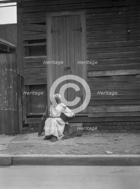 Woman sitting on steps holding a basket, New Orleans, between 1920 and 1926. Creator: Arnold Genthe.