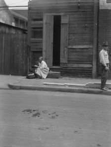 Woman sitting on steps holding a basket, New Orleans, between 1920 and 1926. Creator: Arnold Genthe