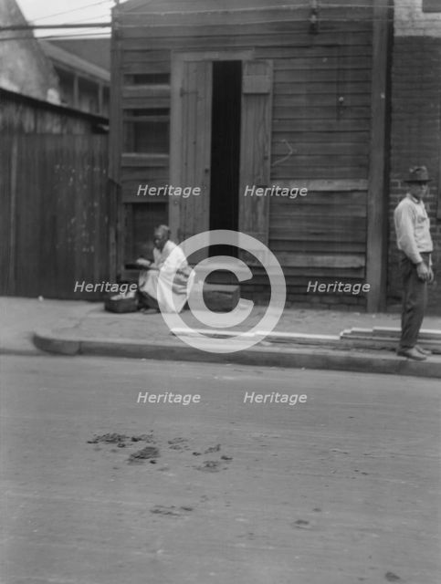 Woman sitting on steps holding a basket, New Orleans, between 1920 and 1926. Creator: Arnold Genthe.