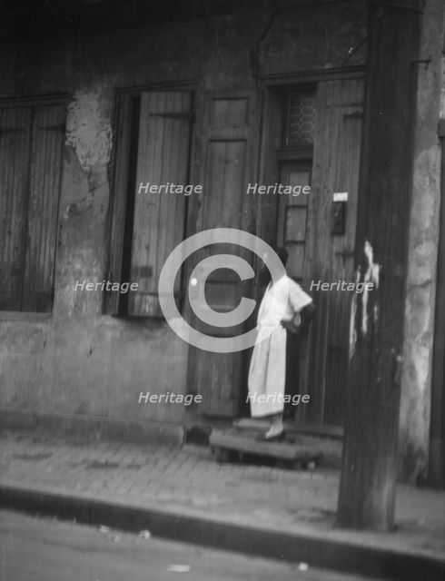 Woman standing in a doorway in the French Quarter, New Orleans, between 1920 and 1926. Creator: Arnold Genthe.