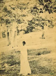 Woman standing in a park, trees in background, c1900. Creator: Eva Watson-Schutze