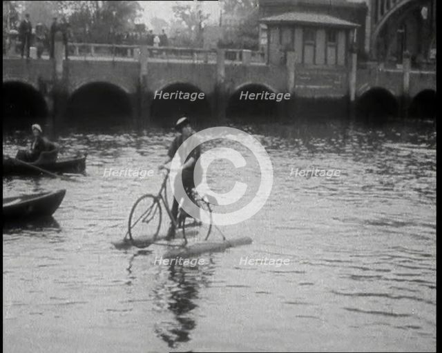 Woman Riding Along a River on a Floating Bicycle Contraption, 1920. Creator: British Pathe Ltd.